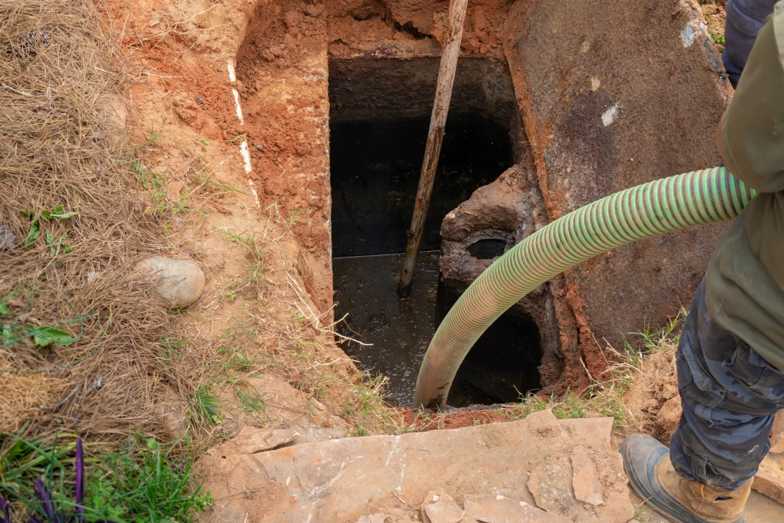 A septic tank opened and being pumped out to remove built-up sludge
